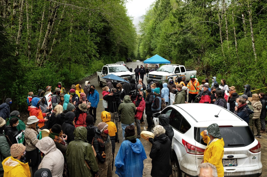 Close to a hundred people pushed an RCMP exclusion zone at Caycuse. Led by Indigenous matriarchs/elders, they occupied the checkpoint. When RCMP called for backup, around 10 people were arrested, including at least two Indigenous youth. During those arrests, media and bystanders were corralled away from the arrests and threatened with arrest if they returned. (Photo and context provided by Mike Graeme)