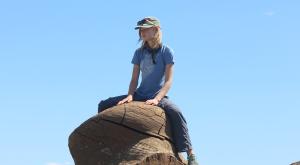 Sadie sitting on a large rock, looking pensive