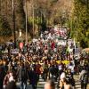 Large crowd marching with signs and banners opposing Trans Mountain